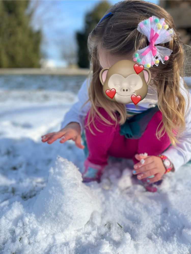 Child shaping a tiny mound of snow.