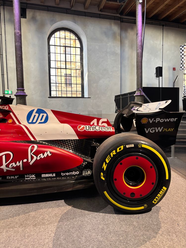 Das Rennauto seitlich mit dem Hinterreifen und flügel dahinter ein Fenster 