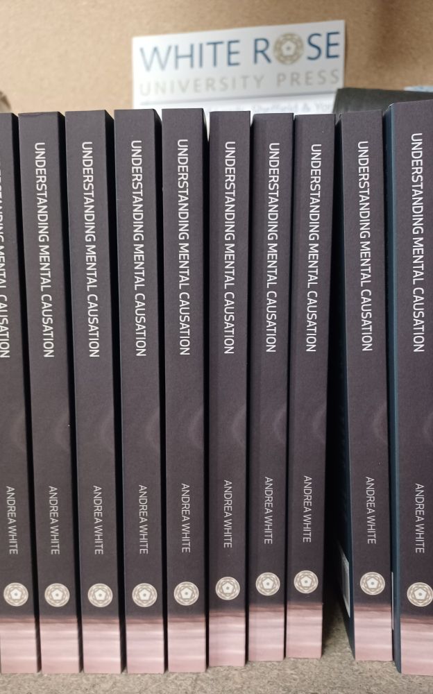 A shelf of books with black spines and the title 'Understanding Mental Causation'