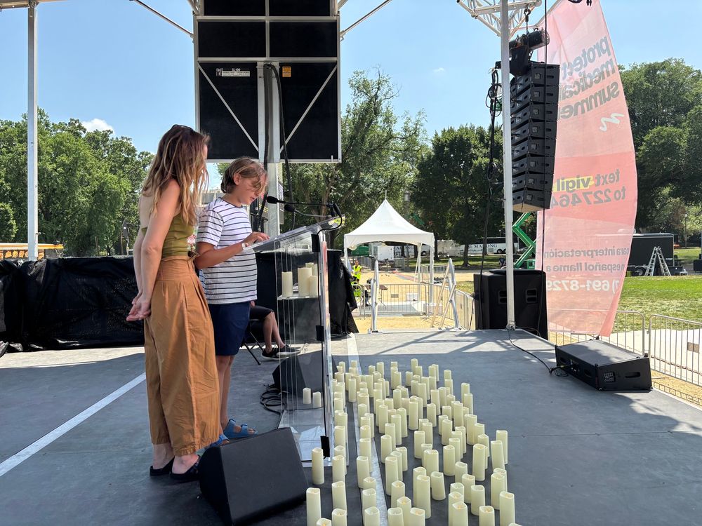 A woman and a young boy standing at a podium on a stage with candles.