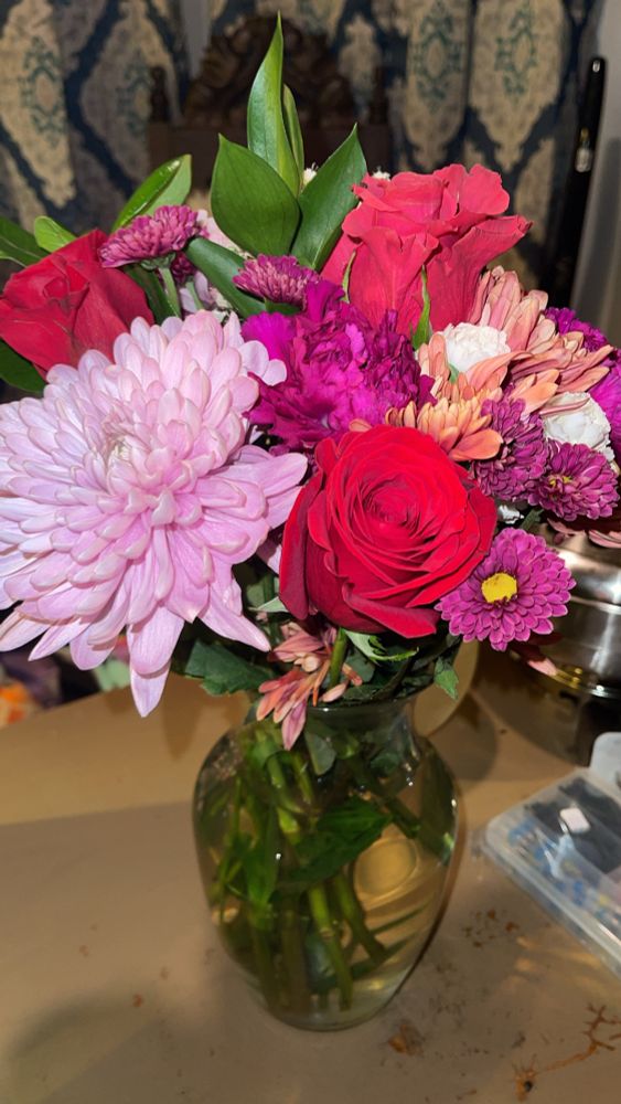 Bouquet of flowers in red, pink, and purple in a clear vase 