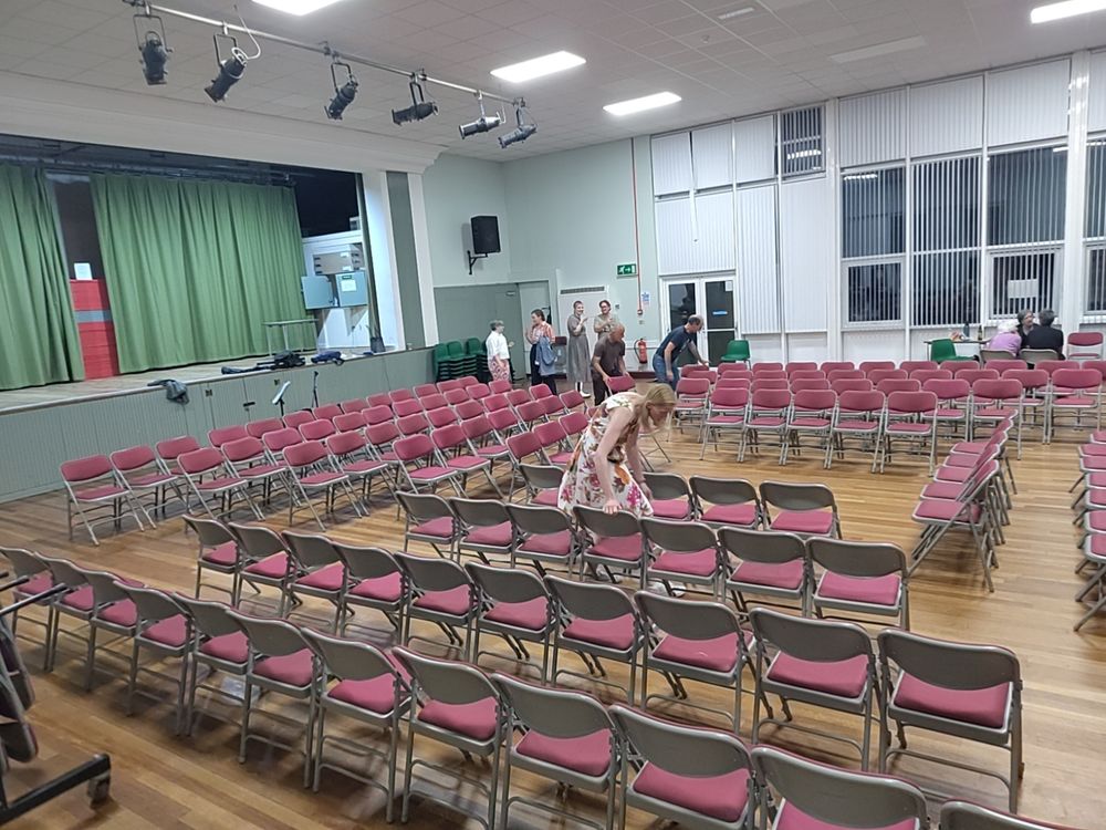 Lots of red chairs being set out in the "hollow square"