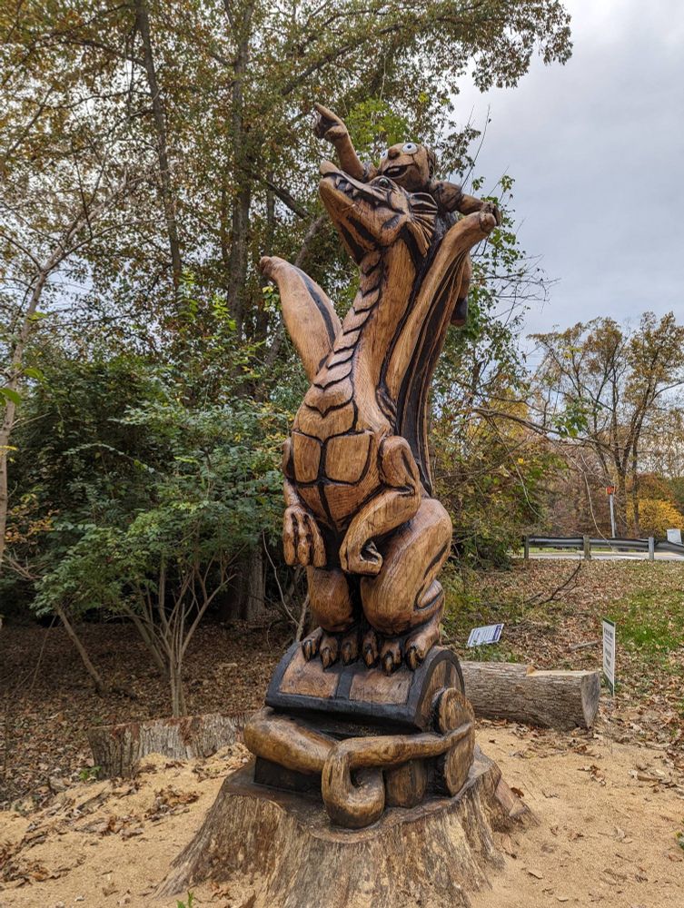 Wooden carved statue of a boy riding a dragon. Puff?