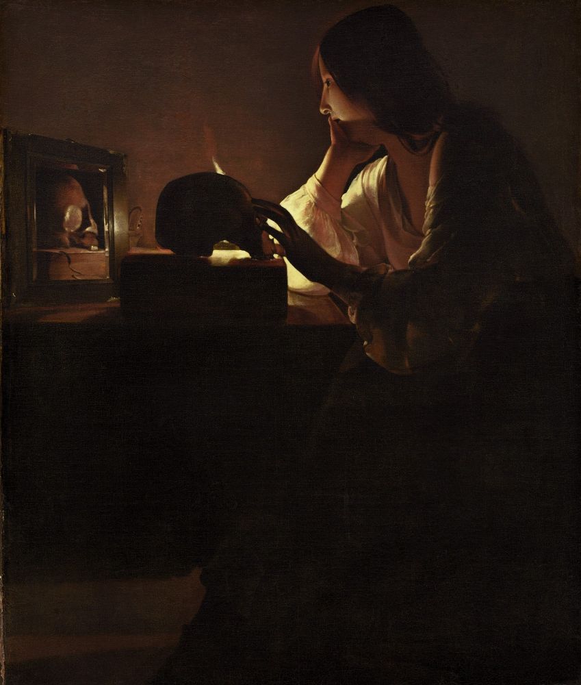 In Georges de La Tour's somber canvas Mary is shown in profile seated at a table. A candle is the source of light in the composition, but the light also carries a spiritual meaning as it casts a golden glow on the saint's face and the objects assembled on the table. The candle light silhouettes Mary's left hand which rests on a skull that is placed on a book. The skull is reflected in a mirror. The skull and mirror are emblems of vanitas, implying the transience of life. (National Gallery website copy)