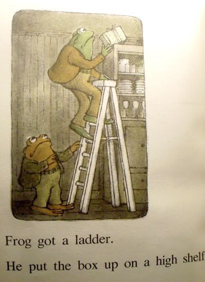 Drawing of anthropomorphized frog and toad in human clothing. One of them is climbing a ladder to place a box on top of a cupboard. Text reads: "Frog got a ladder. He put the box on a high shelf."
