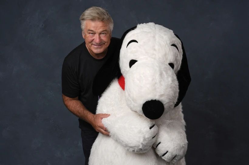 alec baldwin somewhat manically hugging a person in a snoopy suit