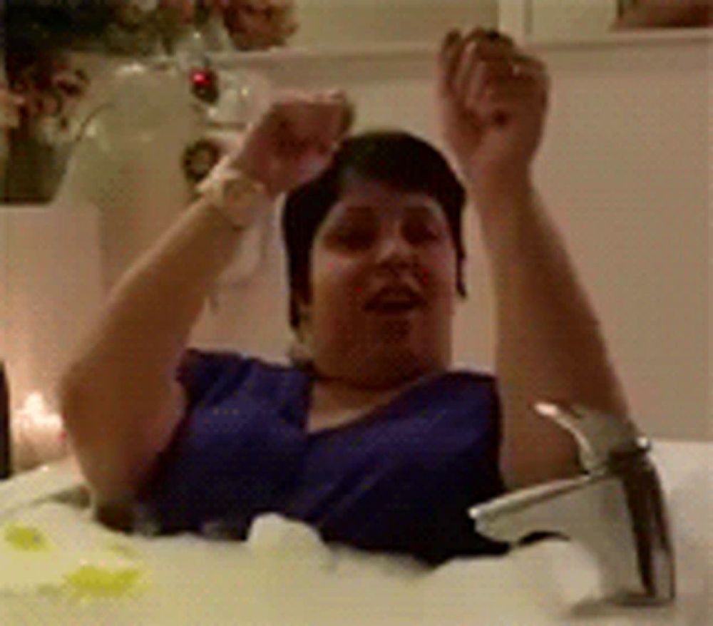 a woman is sitting in a bathtub with her hands in the air