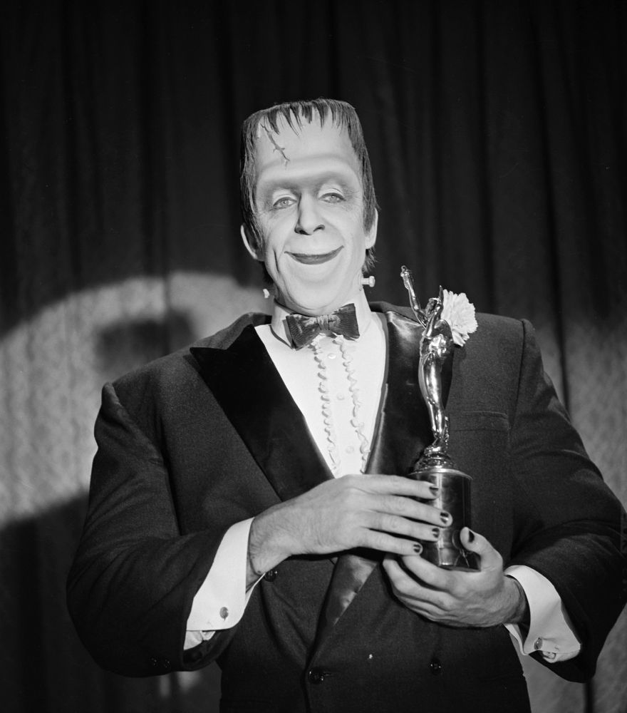 Herman Munster in a fancy suit receiving an award