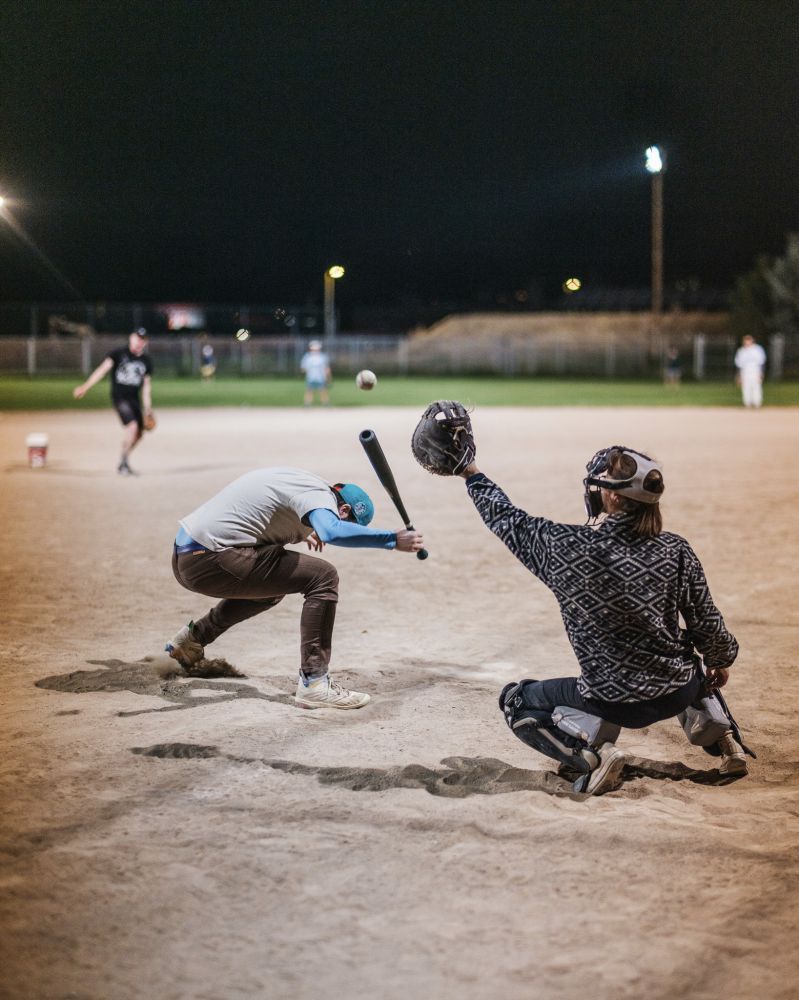 guy dodges a baseball, catcher reaches for it.