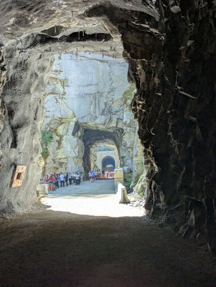 A shot from inside a large tunnel carved out of solid granite. Looking on to the entrance of two other tunnels in the distance.