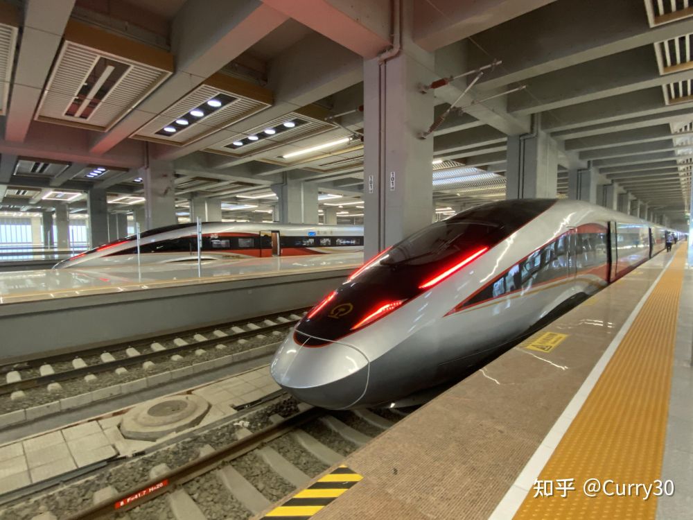 two very futuristic looking Chinese high speed trains in a modern railway station
