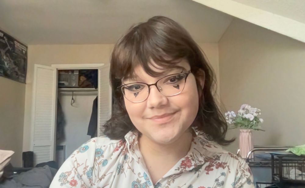 macbook selfie of autumn in a floral shirt in her bedroom