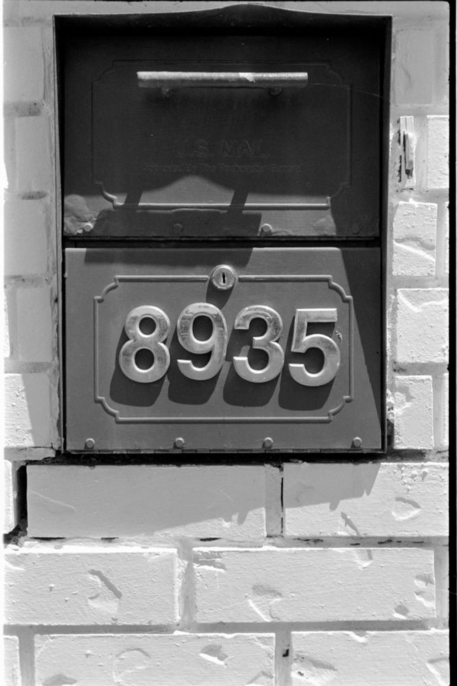 Black & white photo is a post box built into a brick mount. 