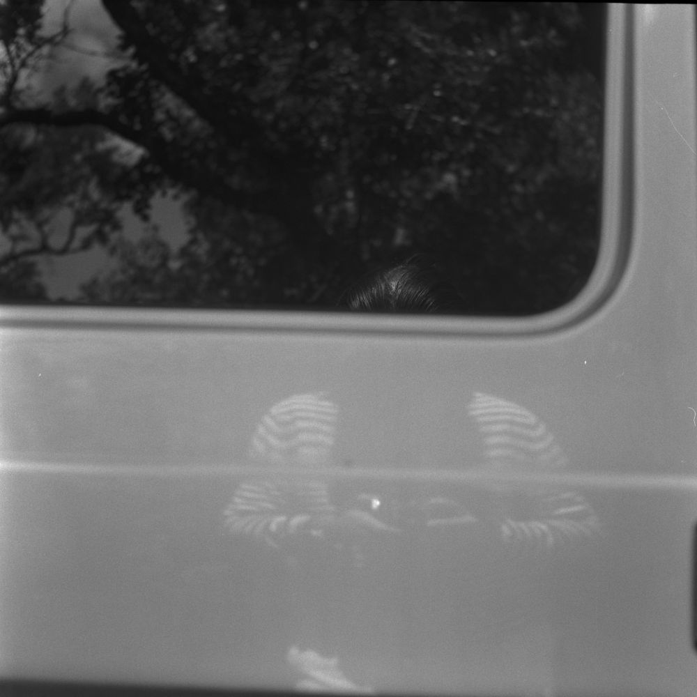 Black & white photo of my reflection in a car door.