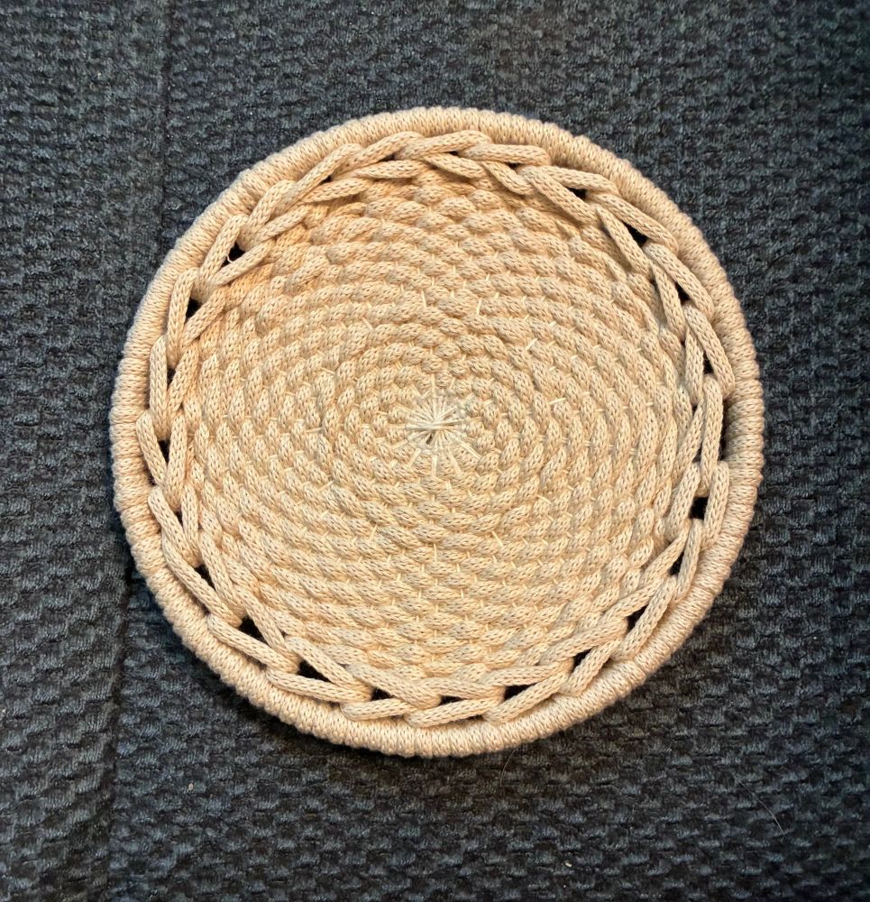 Finished round, woven trivet in natural cord color.