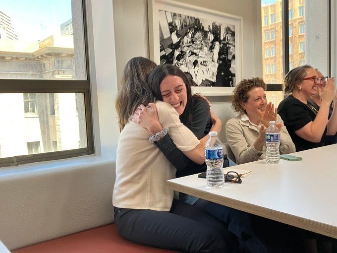Two reporters hug after learning they are finalists for the Pulitzer
