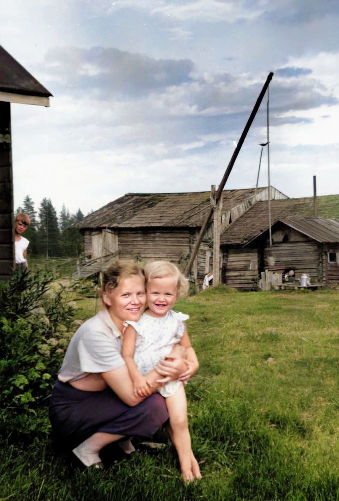 A woman and little girl with an old farmhouse showing in the background.
