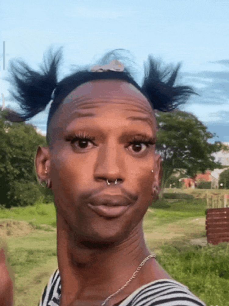 a man with pigtails on his head and a nose ring looks at the camera