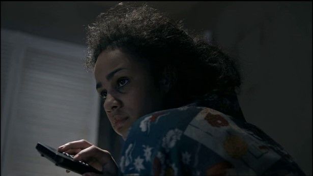 A character from a reconstruction in Dreams of a Life holds a television remote control.