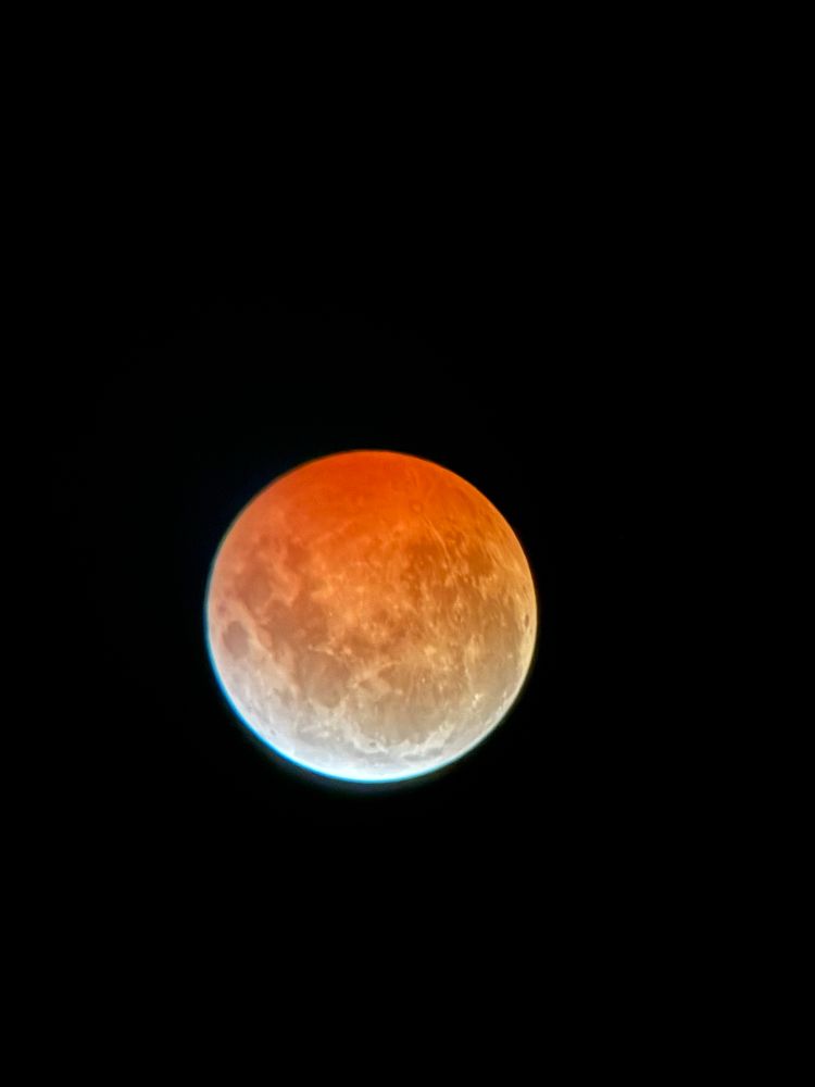 The moon glowing red and viewed via telescope during a lunar eclipse. 
