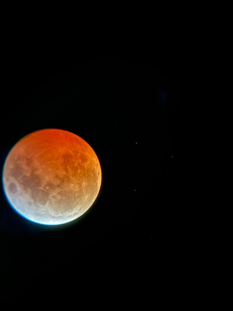 The moon viewed through a telescope and appearing red from the lunar eclipse. 