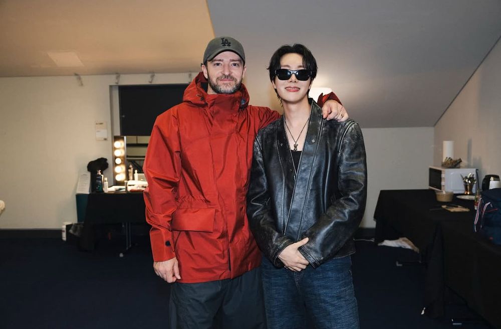 Justin Timberlake and Hobi. JT has on a baseball cap and a big red coat. Hobi is wearing shades and a black leather jacket.