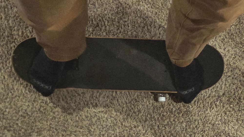 The poster (me) in his sock feet standing on an old skateboard deck, balancing on a one liter bottle of club soda.