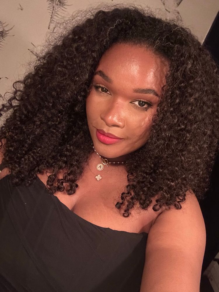 Selfie of a Black woman with dark hair and a black corset top 