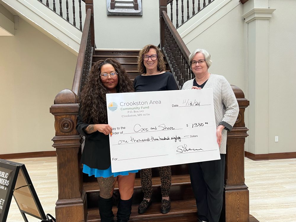 Grant fund awardee from Crookston’s Care & Share with 2 CACF committee members holding oversize award “check”
