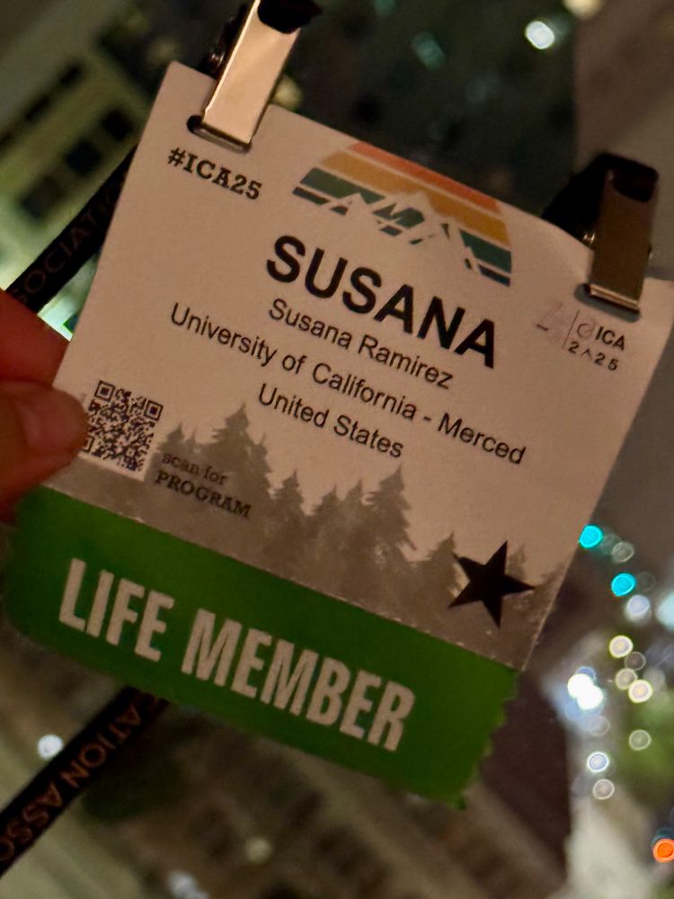 Photo of a closeup name badge Susana Ramirez ICA conference 2025 with green sticker “life member”. Hand is holding badge up against a window. It’s night outside and city lights