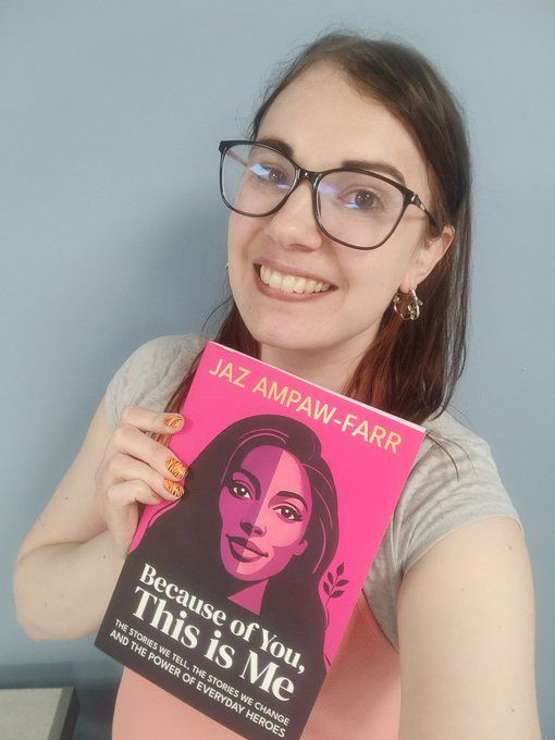 Kat holding a copy of 'Because of You, This is Me' by Jaz Ampaw-Farr. Book descriptor reads: "The stories we tell, the stories we change and the power of everyday heroes."