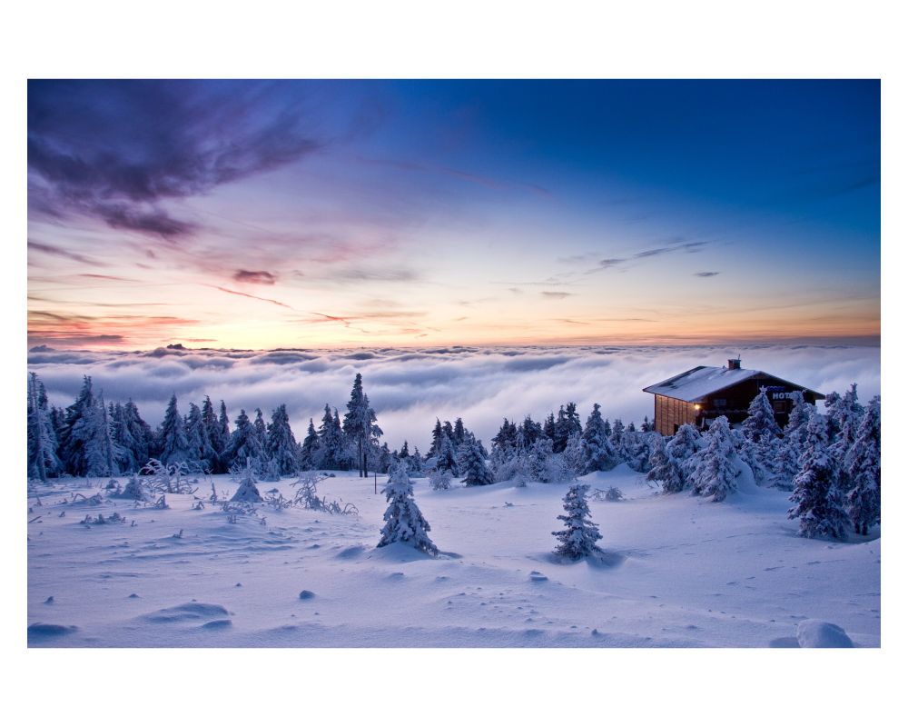 A small building on top of a snowy mountain, over the clouds 