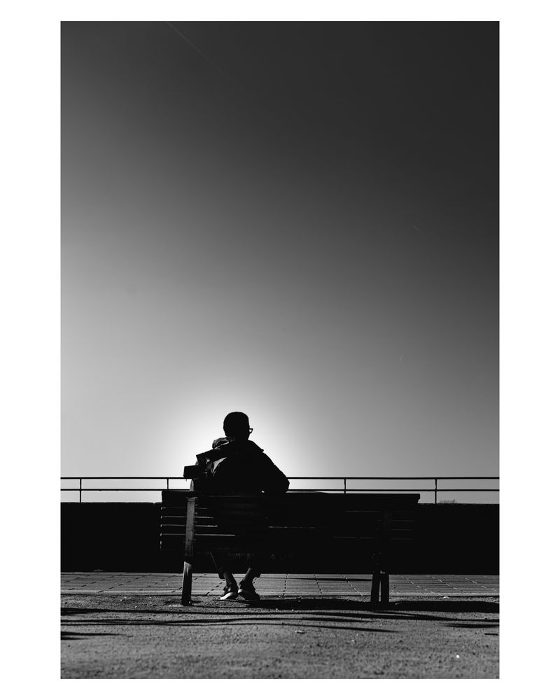 A photo of one person on a bench. Black and white. 