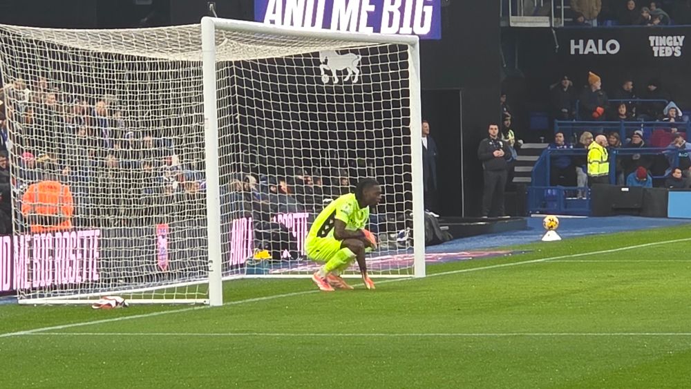 AO in his classic crouch position in goal, one hand on the ground looking forward
