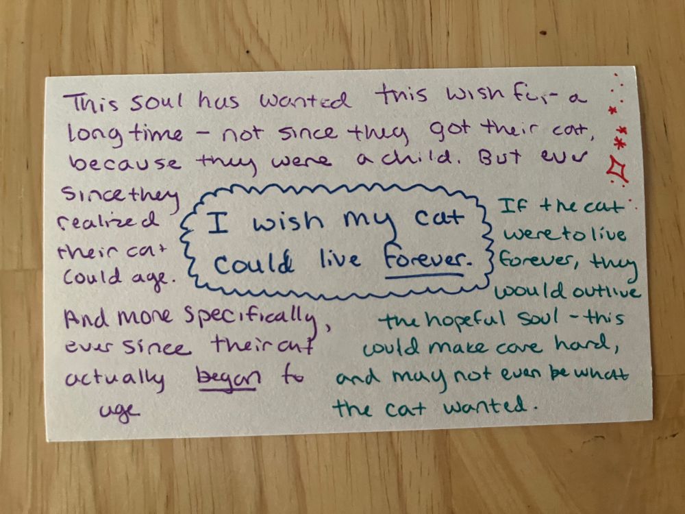 A Wish Card for a playtest of By Way Of Starlight. The color-coded writing on the card reads: 

(The Wish) I wish my cat could live forever. 

(Info about the Person) This soul has wanted this wish for a long time - not since they got their cat, because they were a child. But ever since they realized their cat could age. And more specifically, ever since their cat actually began to age. 

(Info about the Wish) If the cat were to live forever, they would outlive the hopeful soul - this could make care hard, and may not even be what the cat wanted. 

Little red stars are doodled in the top right corner. 