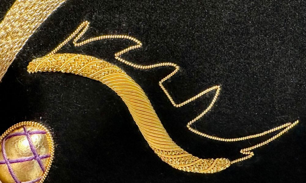 Finished cutwork S shape in alternating bright wire check and rough purl, next to pearl purl outline.