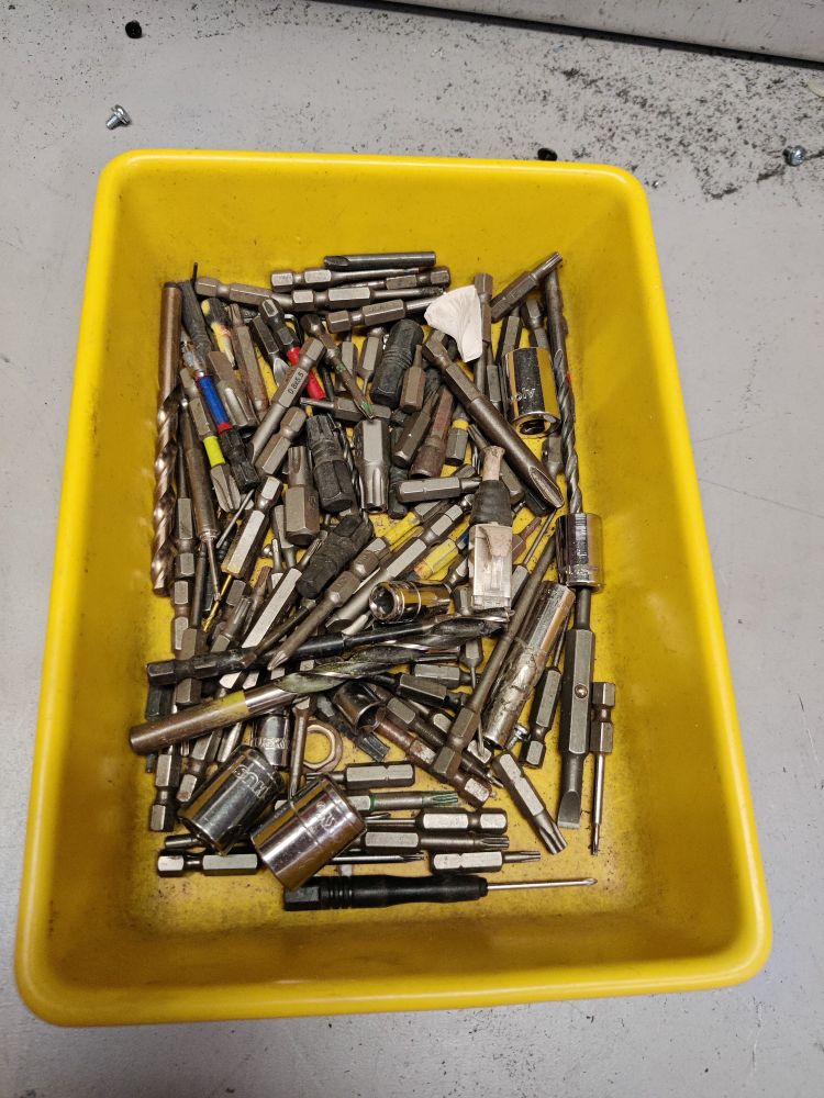 A disorganized tray of drill bits. 
