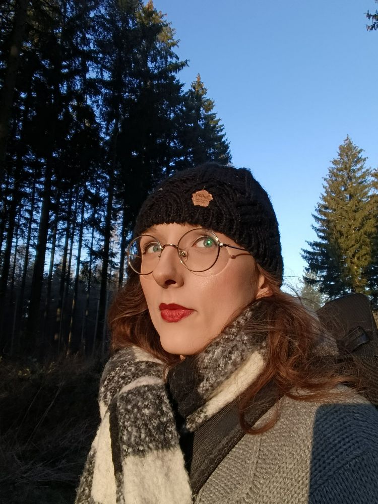 me standing in the woods, against a cloudless blue sky in the back. the sun is shining on my face. 