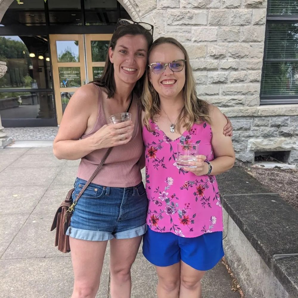 Two women standing together smiling and holding champagne