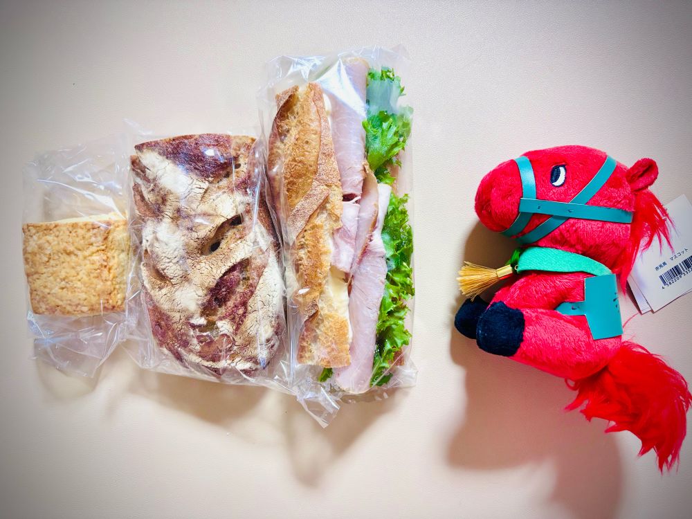 スコーン、りんごパン、ハムのバケットサンド、赤兎馬のぬいぐるみが並んでいる