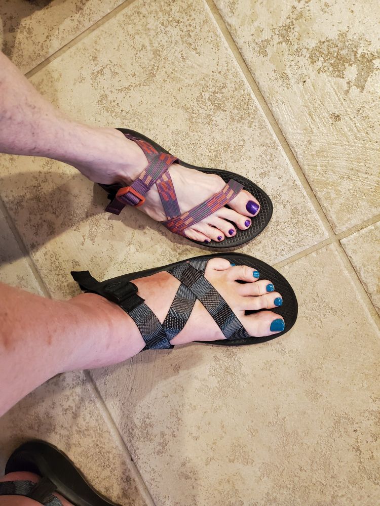 Feet, one with purple nails and the other is green.