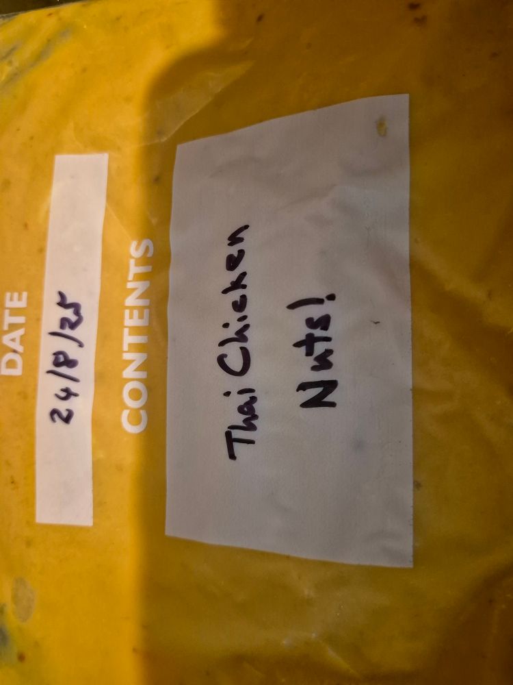 A zip loc bag filled with an orange/yellow soup. On the bag is written "Thai Chicken Nuts!"