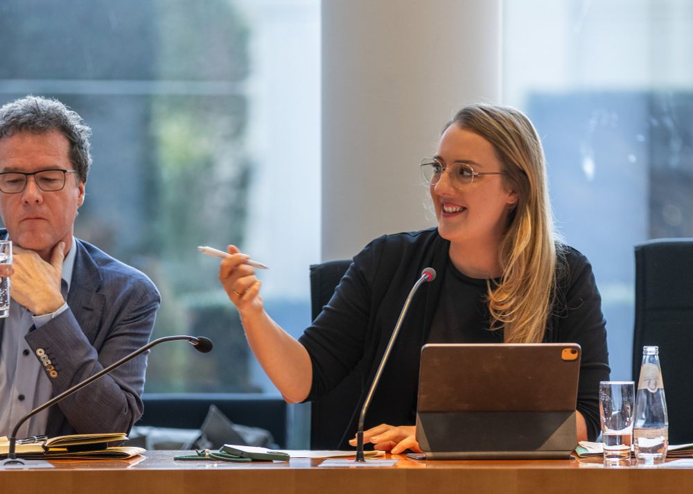 Katharina Dröge sitzt in einem Sitzungssaal, vor ihr ist ein Tischmikrofon zu sehen.