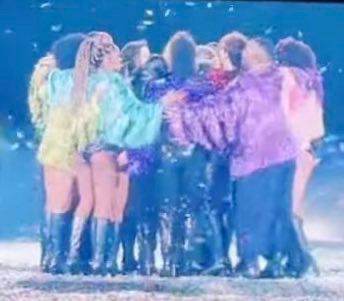 Slightly over saturated /grainy photo of the dancers on the Eras Tour group hugging the closing night of the tour on stage with Taylor