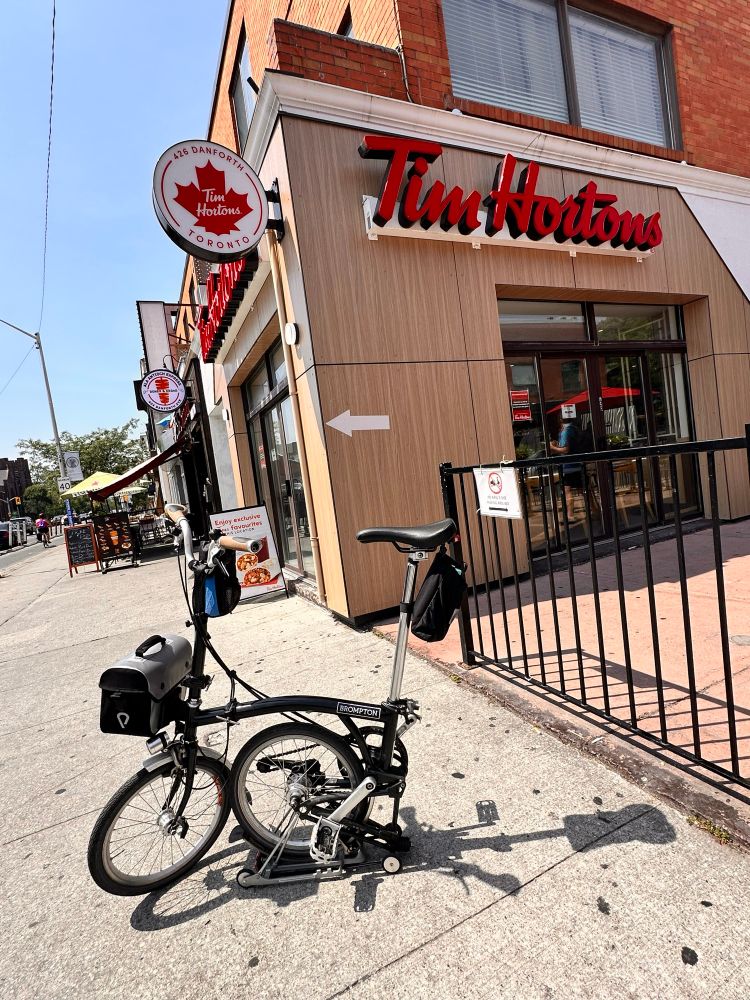 Street scene. Brompton bicycle folded in foreground. Tim Horton’s in background. 