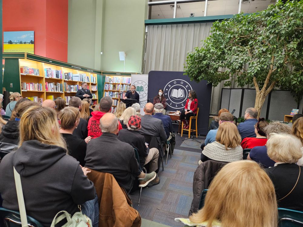A large crowd of people facing the stage where Patty sits. 