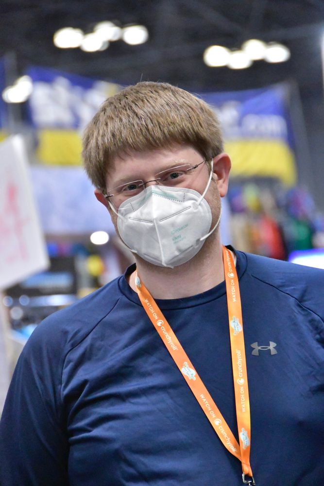 Kevin, wearing glasses, a POWECOM KN95, a blue T-shirt at the New York Comic Con, posed for Julie Lam’s pandemic documentary project.