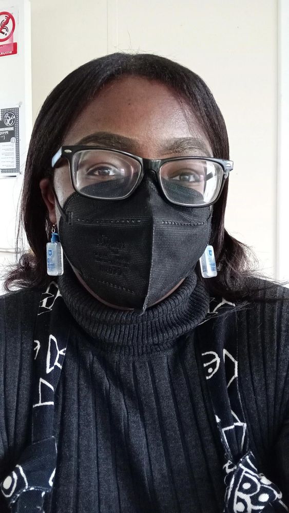 Blezzing Dada, a Black mental health advocate, smiling behind a FFFP2 respirator, black framed glasses, cute earrings in the shape of a disinfectant bottle.
 
Read story on MaskTogetherAmerica’s educational platform: 
Instagram:
https://www.instagram.com/p/DD4sEoIuOAL/?igsh=MXlsMG05d3UyY3dr

Facebook: https://www.facebook.com/share/p/17tCdEZnkE/?