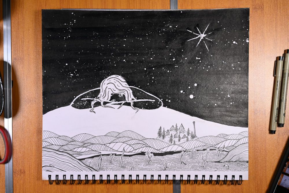 Photo displays a black and white drawing of a night scene. In the foreground, thin plants sprout from a restless pond nestled in a quilt of hills. At the top of the hills sits a tiny village surrounded by trees and marked with a light house. A huge white slope rises behind the village, a woman made of night sky rests at the top observing the town. The sky above is black, dotted with stars. 