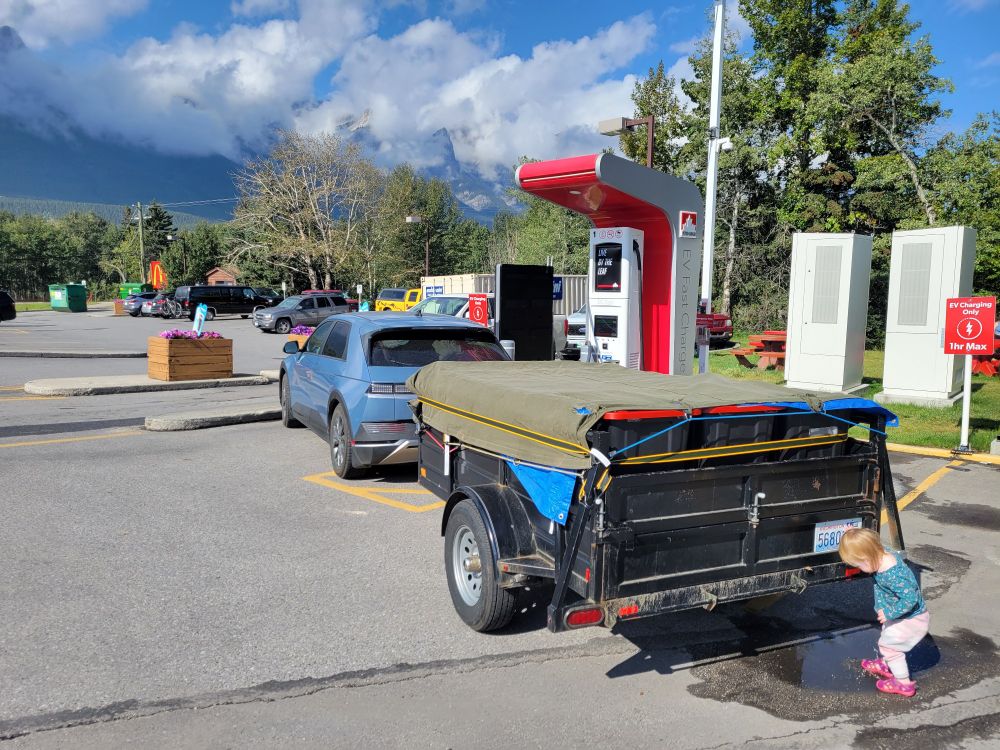 An Ioniq 5 charging while towing a utility trailer. 